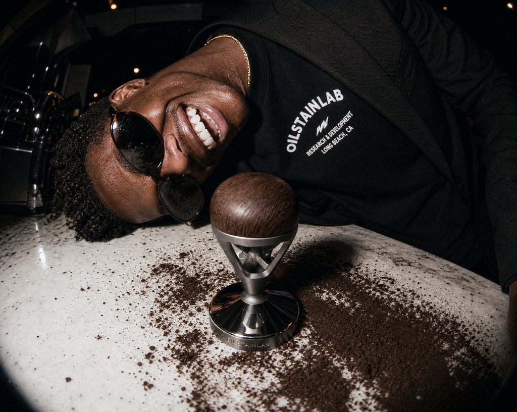 Close-up of the HF-11 coffee tamper showing the aerospace-grade CNC aluminum and warm wooden grip inspired by classic car shifters.