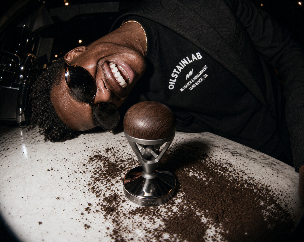Close-up of the HF-11 coffee tamper showing the aerospace-grade CNC aluminum and warm wooden grip inspired by classic car shifters.